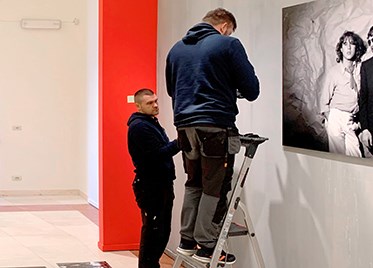 Two ushers from Authenticphoto place an opener on the wall.